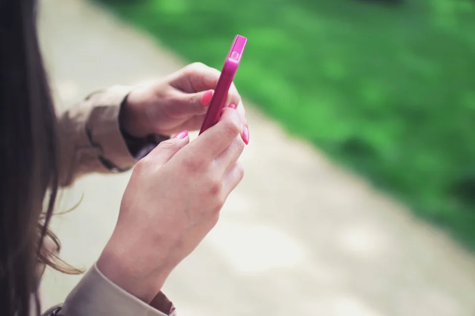 ピンクのスマートフォンを使う場面